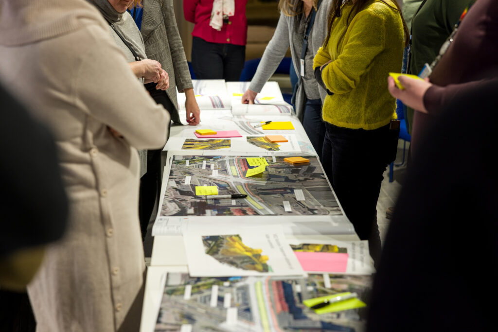 henkilöitä suunnitelmien äärellä tutustumassa eri vaihtoehtoihin 