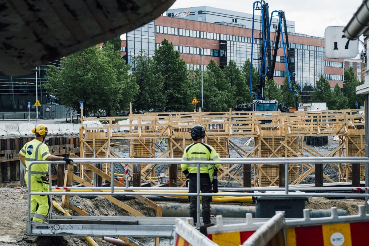 Kaksi työmiestä katsoo siltatyömaalle päin.